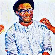A person wearing glasses and a casual shirt is smiling, with two hands on their shoulders.