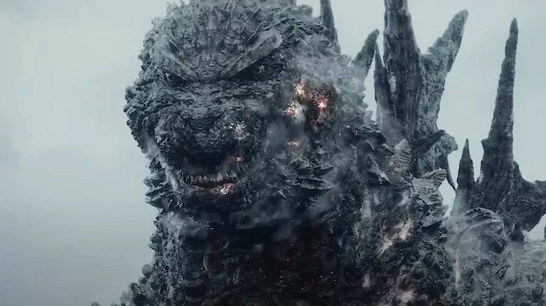 A close-up of Godzilla, a giant, reptilian monster, with glowing eyes and smoke emanating from its rough, rocky skin.