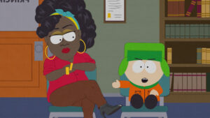 ‘South Park: Joining The Panderverse’ Blu-Ray Review – All Roads Lead To Disney A cartoon woman with glasses and a headscarf sits cross-legged, arms folded. Next to her, a young boy in a green hat gestures as he speaks. They are in a room with bookshelves and a certificate on the wall.