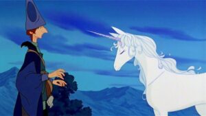 A wizard wearing a tall hat stands next to a white unicorn against a backdrop of mountains and a blue sky.