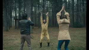 ‘To The Moon’ Blu-Ray Review – Psychological Slow Burn Is A Rewarding Discovery Three people perform an outdoor exercise routine in a forest, standing in a triangle formation. The person in the middle raises their hands while the two on the sides clap above their heads.