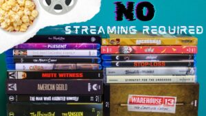 A collection of DVDs and Blu-rays is stacked on a table with some popcorn in the corner. The text reads "No Streaming Required." A film reel is also visible in the image.