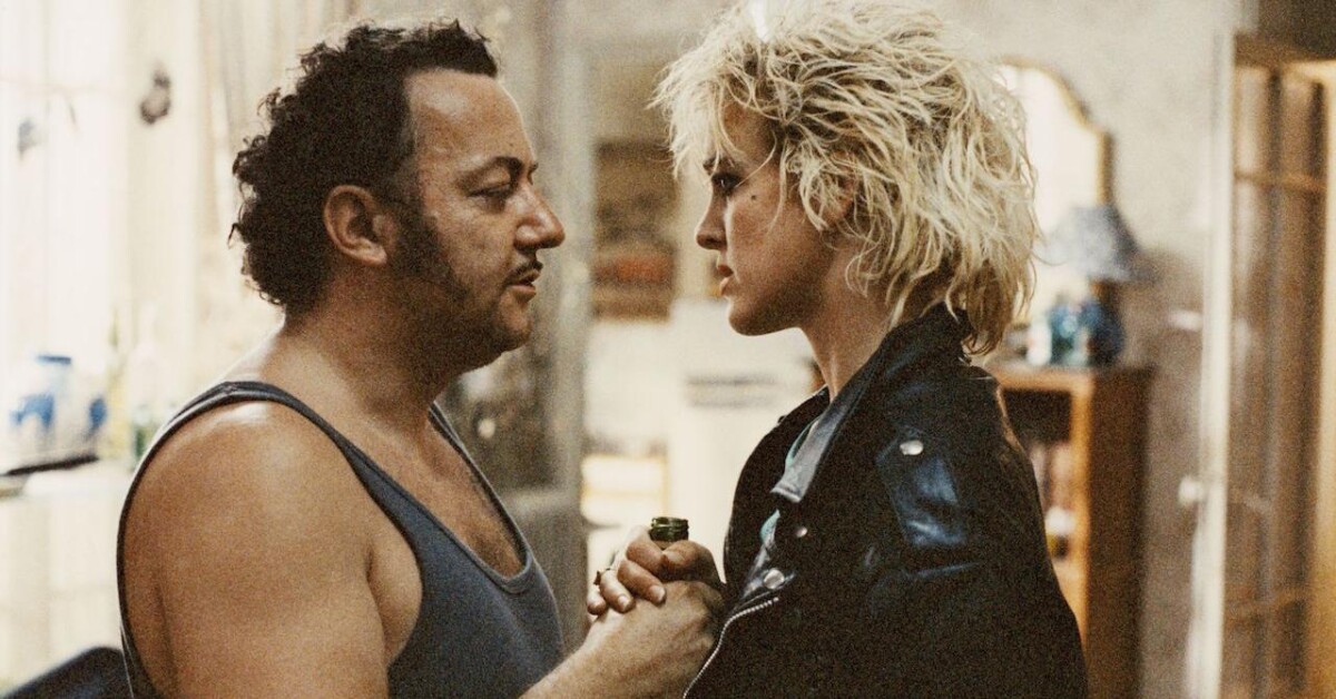 Man in a tank top and woman with short, blonde hair and a leather jacket face each other in an intense moment.