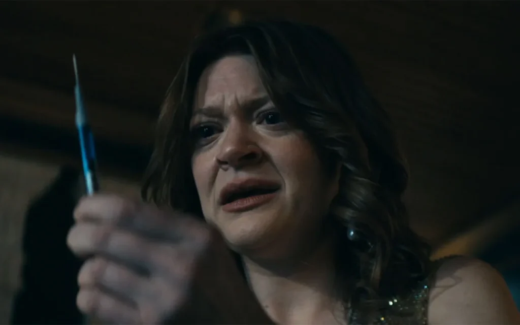A woman with a concerned expression looks intently at a syringe she is holding.