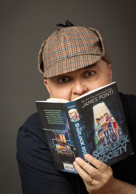 A person wearing a deerstalker hat is reading a book titled "Sherlock Society" by James Ponti.