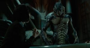 A person holds a small object while facing a tall humanoid creature with amphibian features in a dimly lit industrial setting.