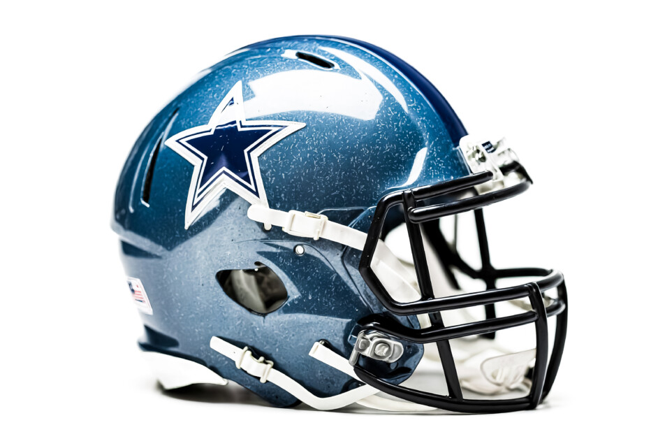 A Dallas Cowboys football helmet, isolated on a white background. The helmet is blue with a white star on the side. The helmet is also equipped with a black face mask. The photo is taken at a slightly high angle.