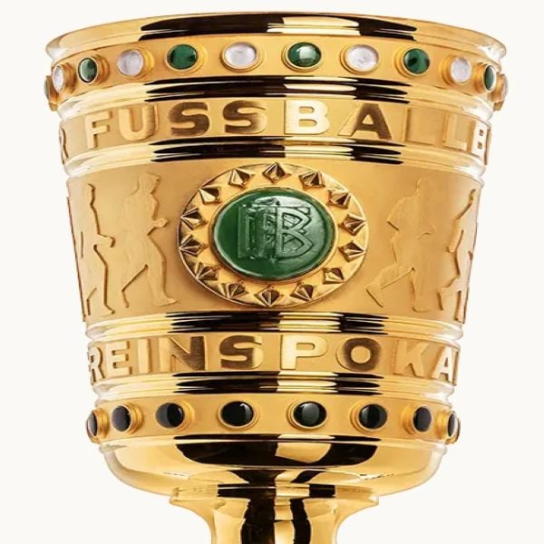 Close-up of a gold trophy with engraved text, decorative green and white studs, and emblem featuring initials.