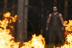A man in a leather outfit stands in a forest, surrounded by flames.