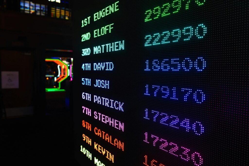 A leaderboard screen displays names and scores, with "1st Eugene" at the top. Colorful lighting in the background.