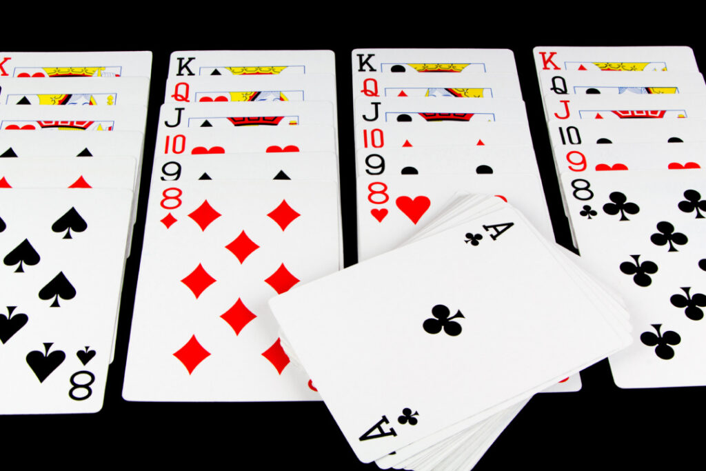 Several decks of playing cards are spread out, showing face cards, number cards, and an ace of clubs on top of an additional stack.