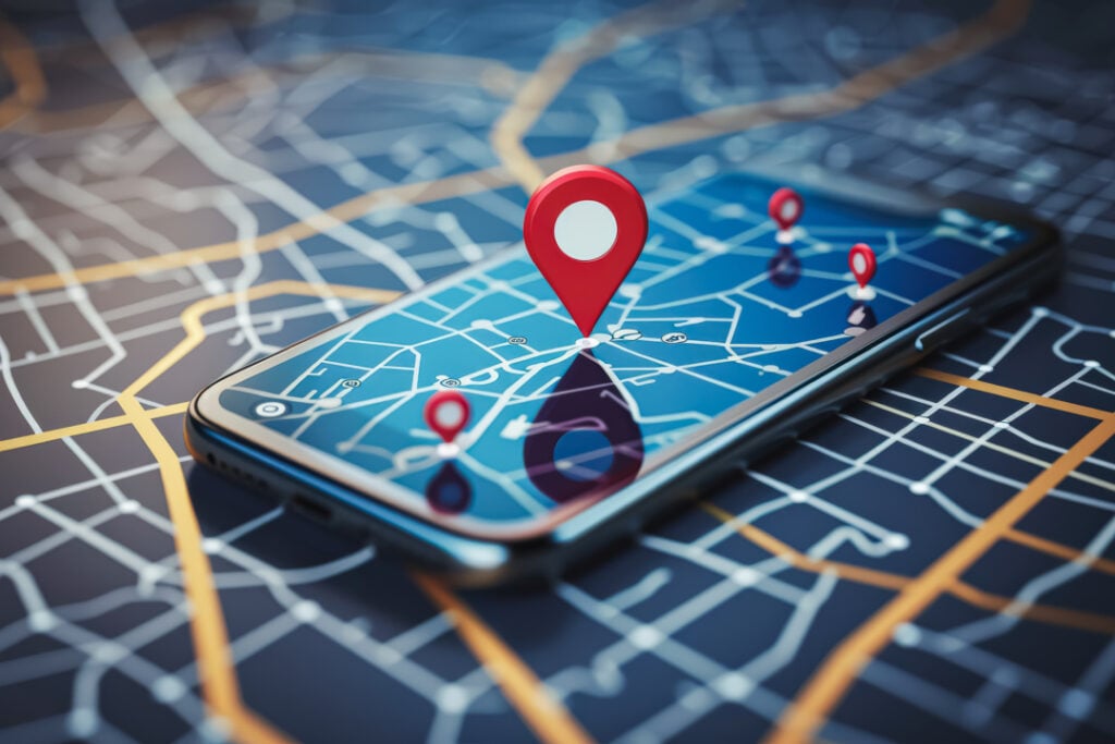 Smartphone displaying a map with red location pins, placed on a street map background.