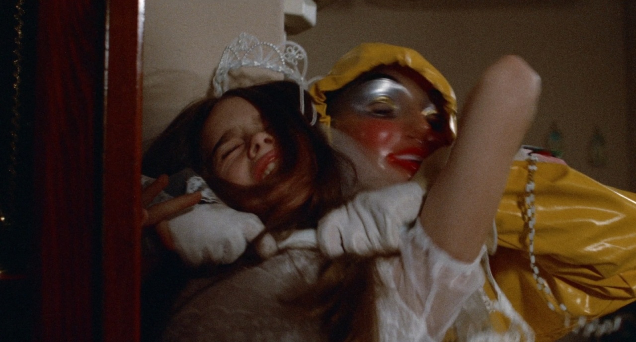 A person in a clown costume grabs a struggling young girl wearing a white dress.