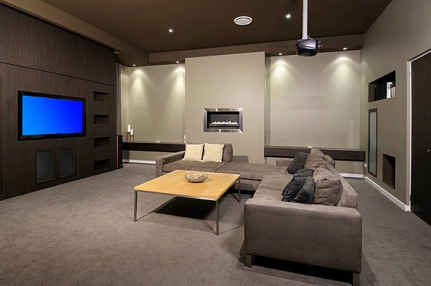 Modern home theater room with a large sofa, a coffee table, a wall-mounted TV, and a built-in fireplace.