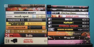 Stack of various DVD cases arranged against a teal background, featuring titles from multiple genres including "Inglourious Basterds" and "Winchester '73.