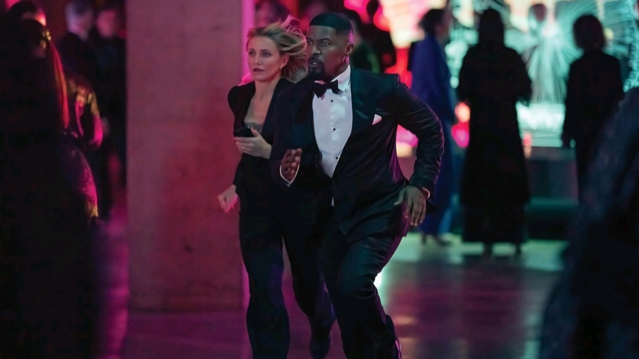 A woman and a man in formal attire appear to be running through a room with colorful lighting.
