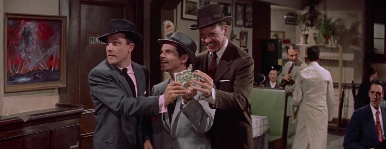 Three men in suits and hats hold money, standing together in a vintage-style room. A diner setting with a waiter in the background.