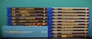 A collection of Blu-ray movie cases, including titles like "Quackbusters" and "The Gumball Rally," stacked in two columns against a blue background.