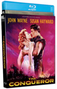 Blu-ray cover of "The Conqueror" featuring John Wayne and Susan Hayward embracing against a red background with a silhouetted battle scene below.