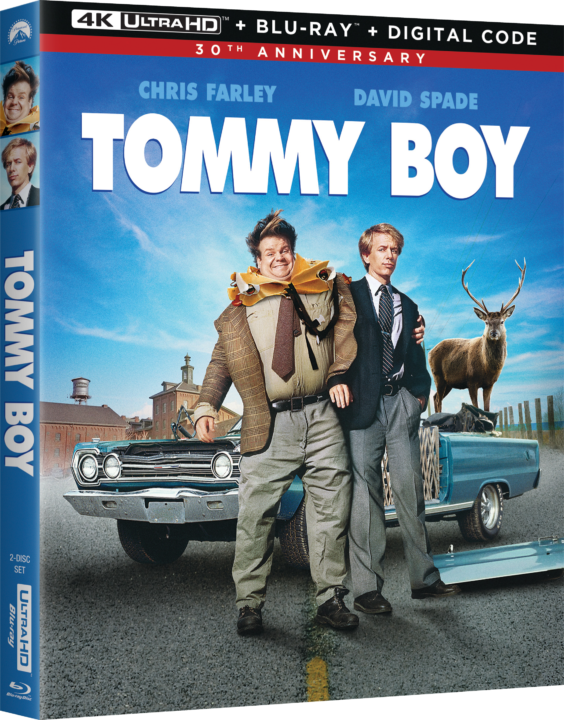 Cover of "Tommy Boy" 30th Anniversary 4K Ultra HD Blu-ray. Two men stand in front of a car with an office building and a deer on the roof in the background.
