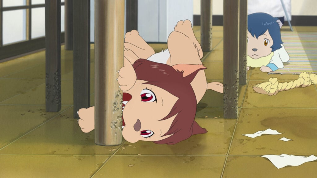 Animated scene of two children with wolf-like features playing under a table. One, with brown fur and eyes, chews a table leg, while the other, with blue hair, watches nearby.