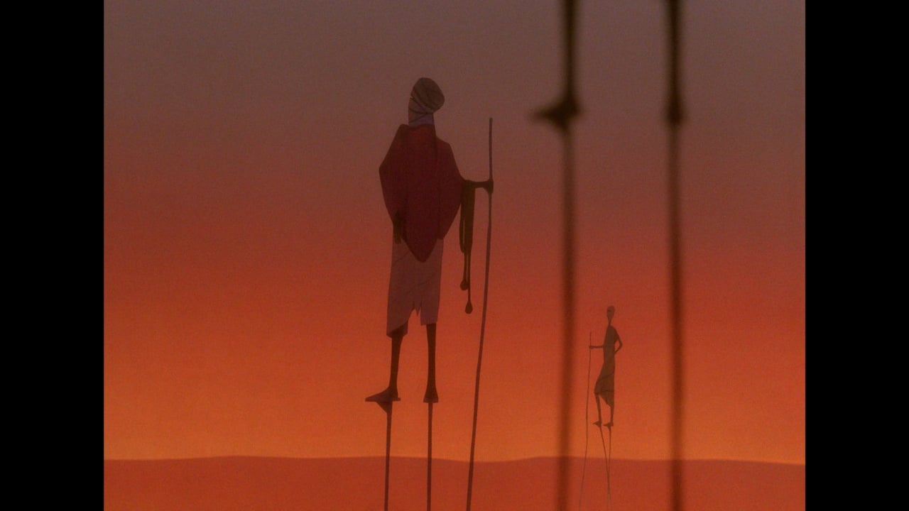Two figures walking on stilts in a desert landscape with an orange sky, wearing traditional clothing and carrying long staffs.