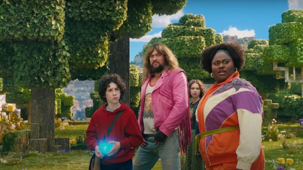 A group of four people stands in a pixelated forest, one holding a glowing object. They wear colorful, varied outfits, and look towards something in the distance.