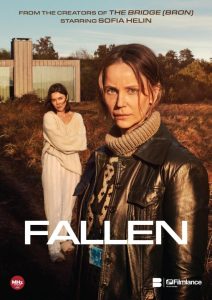 Two women stand outdoors in front of a modern house; one is in the foreground wearing a leather jacket and scarf, the other stands in the background in light clothing. Text reads "Fallen.