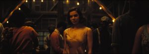 Warner Bros. To Release Ryan Coogler’s Hit Horror Film ‘Sinners’ On 4K UHD Blu-Ray This July A woman in a light dress stands in a dimly lit room filled with people and hanging lights.