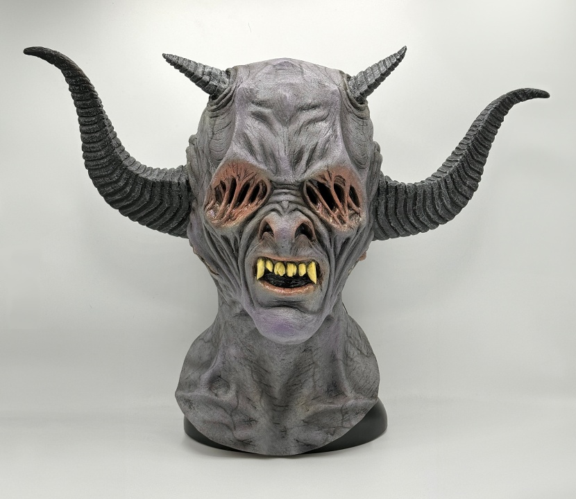 A bust of a horned, gray-skinned creature with sharp yellow teeth, sunken eyes, and ridged horns, set against a plain background.