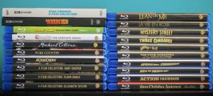 No Streaming Required: Physical Media Spotlight For The Week Of June 10th – James Bond & Exploring The Warner Archive A collection of Blu-ray and 4K UHD movie cases is arranged neatly in two stacks against a teal background. Titles and genres vary.