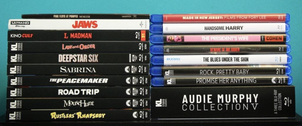 A collection of DVD and Blu-ray movie cases stacked in two columns, including titles like "JAWS," "Law and Order," and "AUDIE MURPHY COLLECTION V.