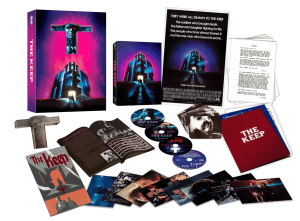 Box set of "The Keep" featuring a case, discs, booklet, poster, replica cross, comic book, lobby cards, and art prints arranged on a black background.