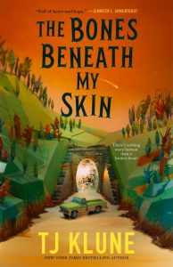 A yellow pickup truck drives through a tunnel in a colorful, stylized landscape under an orange sky. The book title "The Bones Beneath My Skin" by TJ Klune is prominent on the cover.