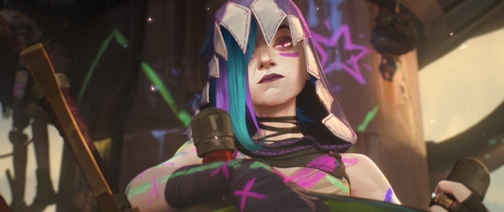 A person with blue and purple hair, wearing a hood and armor with colorful graffiti-like paint, looks forward with a serious expression.