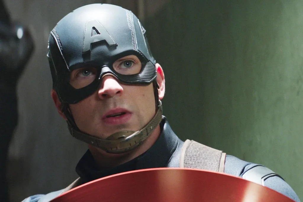 A person dressed as Captain America in costume and mask holds a shield, looking upwards with a serious expression.