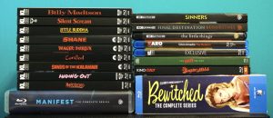 A stack of DVD and Blu-ray cases, including titles like "Billy Madison," "Shane," "Manifest," and "Bewitched: The Complete Series," arranged upright against a teal background.