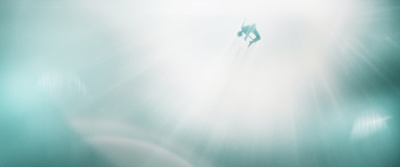A person is suspended underwater, reaching upward toward a bright light source, surrounded by a soft blue and white glow.