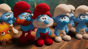 A group of animated Smurfs stands indoors, looking forward with serious expressions, accompanied by a small yellow and orange creature.