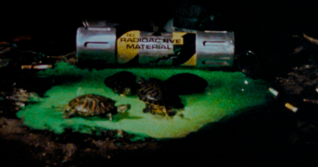 Three small turtles are on a green glowing liquid near a leaking canister labeled "Radioactive Material" in a dark environment.