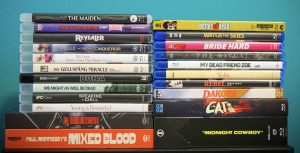 A collection of DVD and Blu-ray movie cases arranged in two stacks against a blue background, featuring various film titles and genres.