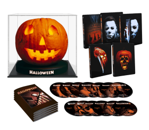 A Halloween-themed box set includes a jack-o'-lantern display, several movie cases with Michael Myers covers, and multiple DVDs arranged in front of a booklet.