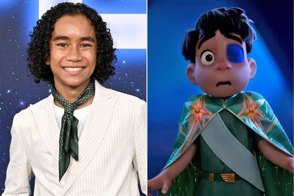 A person with curly hair in a light suit and green scarf stands beside an animated character wearing a cape and eye patch.