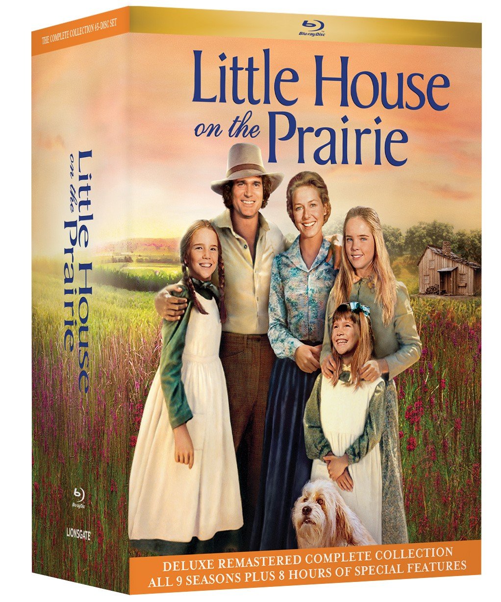 Blu-ray box set of "Little House on the Prairie" shows the main cast in pioneer-era clothing, standing in a rural field with a dog, promoting the complete remastered collection.