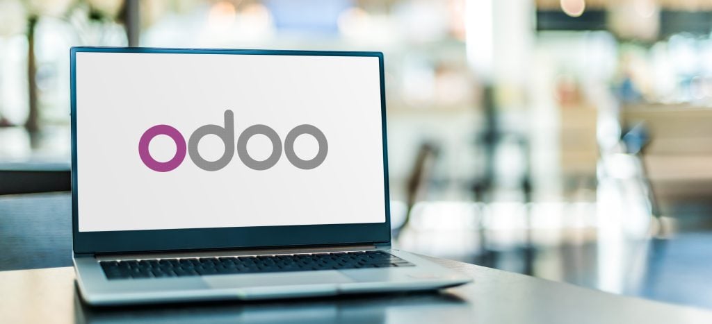 A laptop displaying the Odoo logo on its screen, placed on a table in a bright indoor setting.