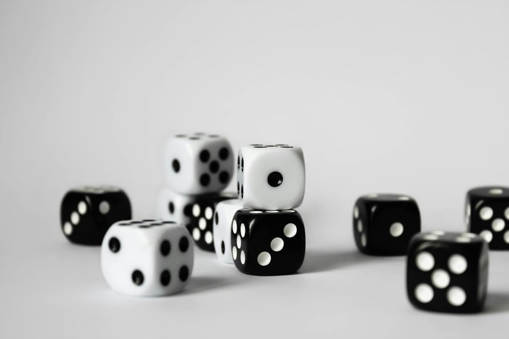 A group of black and white dice are scattered and stacked on a plain, light-colored surface with a neutral background.