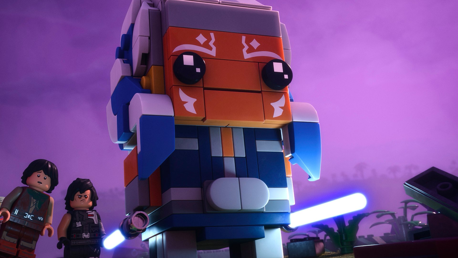 A large LEGO figure with an orange and blue helmet holds blue lightsabers, standing in front of two smaller LEGO characters against a purple sky.