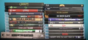 A collection of 21 DVD and Blu-ray movie cases stacked in two columns against a teal background, featuring various film titles and genres.