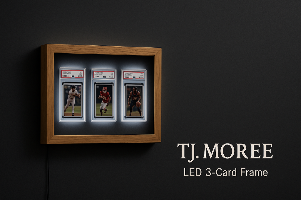 A wooden LED frame displays three graded sports cards, each individually encased and illuminated, mounted on a dark wall beside the text "TJ. MOREE LED 3-Card Frame.