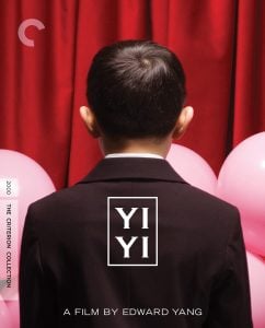 A boy in a suit stands with his back to the camera in front of a red curtain, surrounded by pink balloons. Text reads “YI YI, A Film by Edward Yang.”.